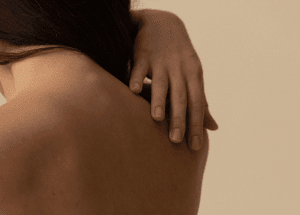 Person berührt mit der Hand ihren Rücken
