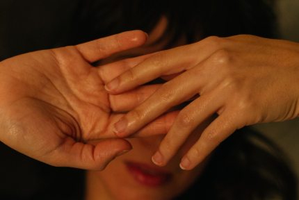 Close-up of two hands gently touching each other, muted colours in the background.