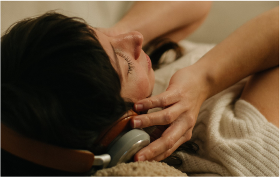 Woman with tan skin and dark hair, wearing headphones and eyes closed, seen from above in a relaxed moment.